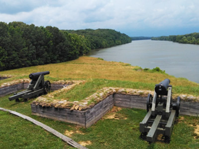 A battery of Civil War era cannons overlook a bend in a river.